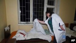 O asistentă curăță lenjeria de pat a unui pacient care a fost rănit după un atac rusesc asupra unui spital de psihiatrie din Harkov, pe 27 aprilie.