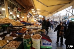 Iranians walk past shops selling dried fruits and nuts at the Grand Bazaar in Tehran on January 20.