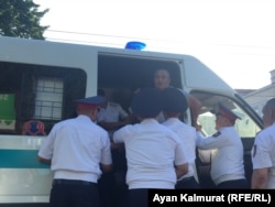 Полицейские заталкивают задержанного рядом с площадью Астана человека в служебный микроавтобус. Алматы, 6 июля 2018 года.