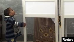  boy looks up at his mother reading her ballot paper before casting her vote during a third round of voting in parliamentary elections in Toukh, El-Kalubia governorate.