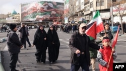 Oameni trec pe lângă un banner patriotic mare reprezentând steagul iranian pe Piața Enghelab în Teheran. 14 ianuarie 2026.