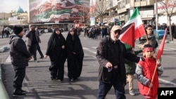 Луѓе поминуваат покрај голем патриотски транспарент со иранското знаме на плоштадот Енгелаб во Техеран на 14 јануари 2026 година.