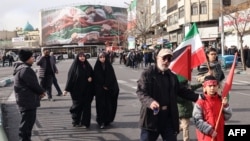 People walk past a large patriotic banner depicting the Iranian flag on Enghelab Square in Tehran on January 14, 2026.