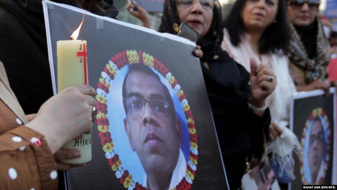 People hold candles in front of a portrait of the Sri Lankan worker who was lynched by a mob over allegations of blasphemy in Lahore in December.