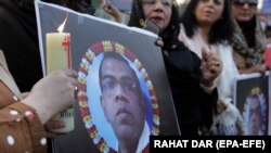 People light candles in front of a portrait of Priyantha Kumara, who was lynched by a mob over allegations of blasphemy, in Lahore, Pakistan, on December 9.