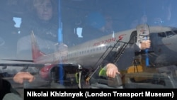 Пассажиры в салоне аэродромного автобуса, проезжающего рядом с самолетом авиакомпании «Россия». Иллюстративное фото.