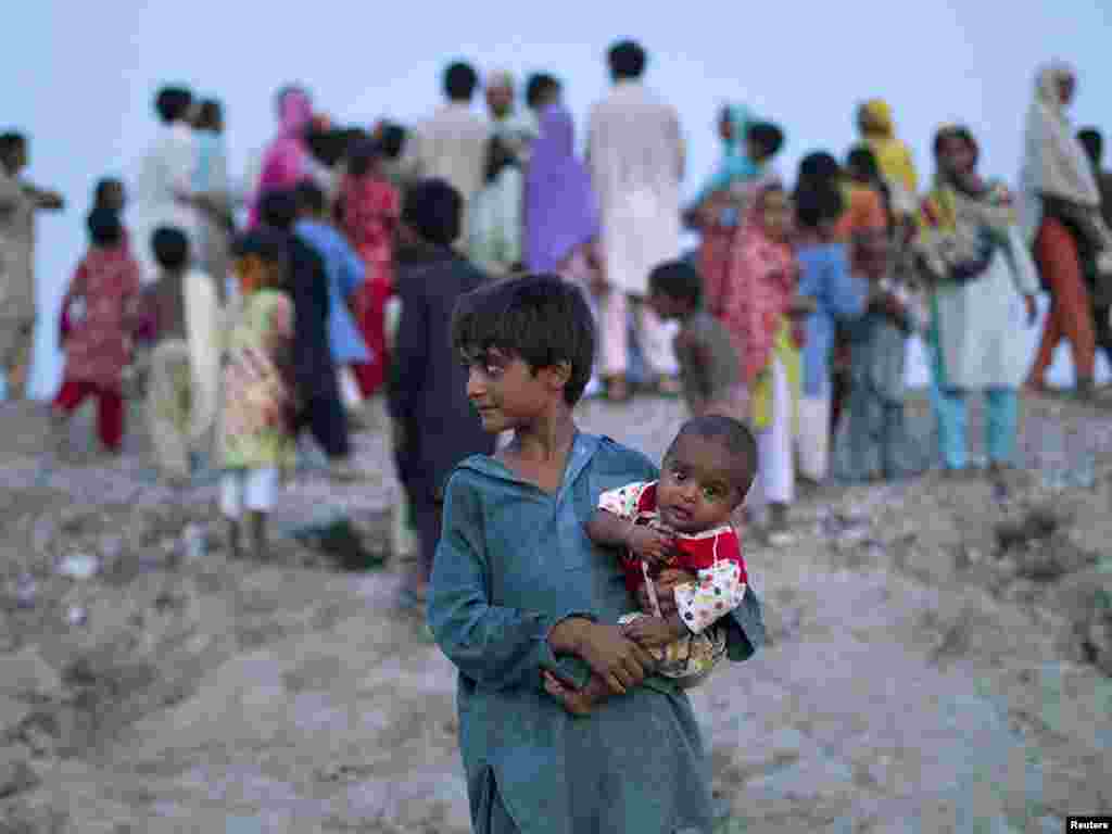 A boy holds his sibling as flood victims wait on a roadside for food handouts from motorists in Pakistan's Muzaffargarh district in Punjab Province on August 11. Photo by Adrees Latif for Reuters