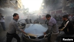 Palestinians try to remove the remains of a car after an Israeli air strike in Gaza City on November 14.