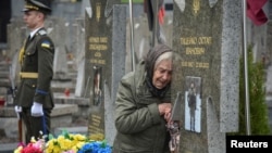  Украинанын батышындагы Львов шаарындагы көрүстөндө согушта каза болуп, ошол жерге коюлган жакынынын мүрзөсүнүн жанында турган аял. 2025-жылдын 23-майы.