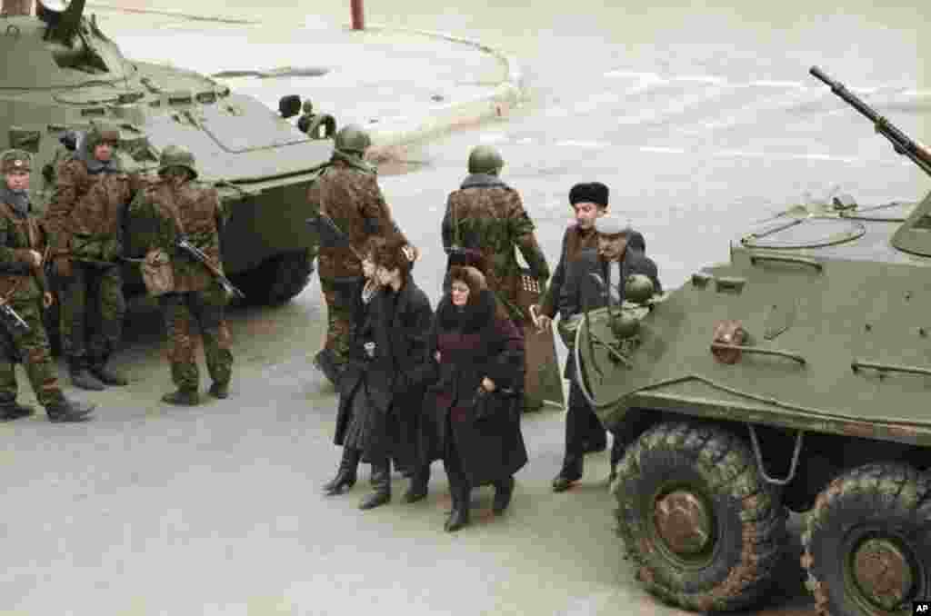 Azerbaijani women walk between a pair of Soviet tanks in Baku on January 28.