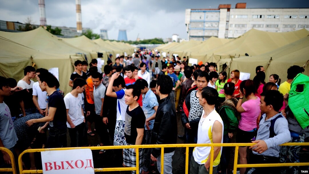 People who were detained during police raids on Moscow markets stand in a tent camp for illegal migrants in Moscow on August 5.