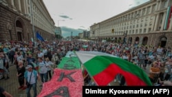 Demonstranti izvikuju parole dok drže veliku bugarsku zastavu sa natpisom "Ostavka" tokom demonstracija u blizini zgrade parlamenta u Sofiji, 22. septembra 2020.