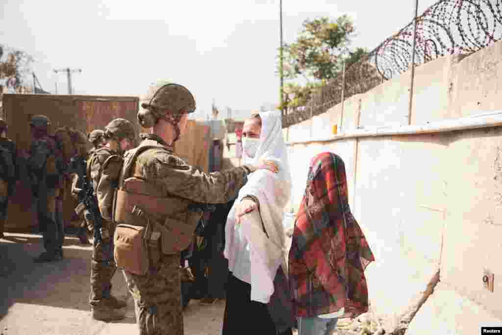 Një zyrtare ushtarake duke kontrolluar dy gra para se të kalojnë në zonën për evakuim jashtë Afganistanit.