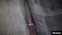 A Pashtun girl peeks through the doorway to her family dwelling in Peshawar.