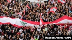 Anti-government protesters shout slogans in Beirut, Lebanon, Sunday, Oct. 20, 2019. Tens of thousands of Lebanese protesters of all ages gathered Sunday in major cities and towns nationwide, October 20, 2019