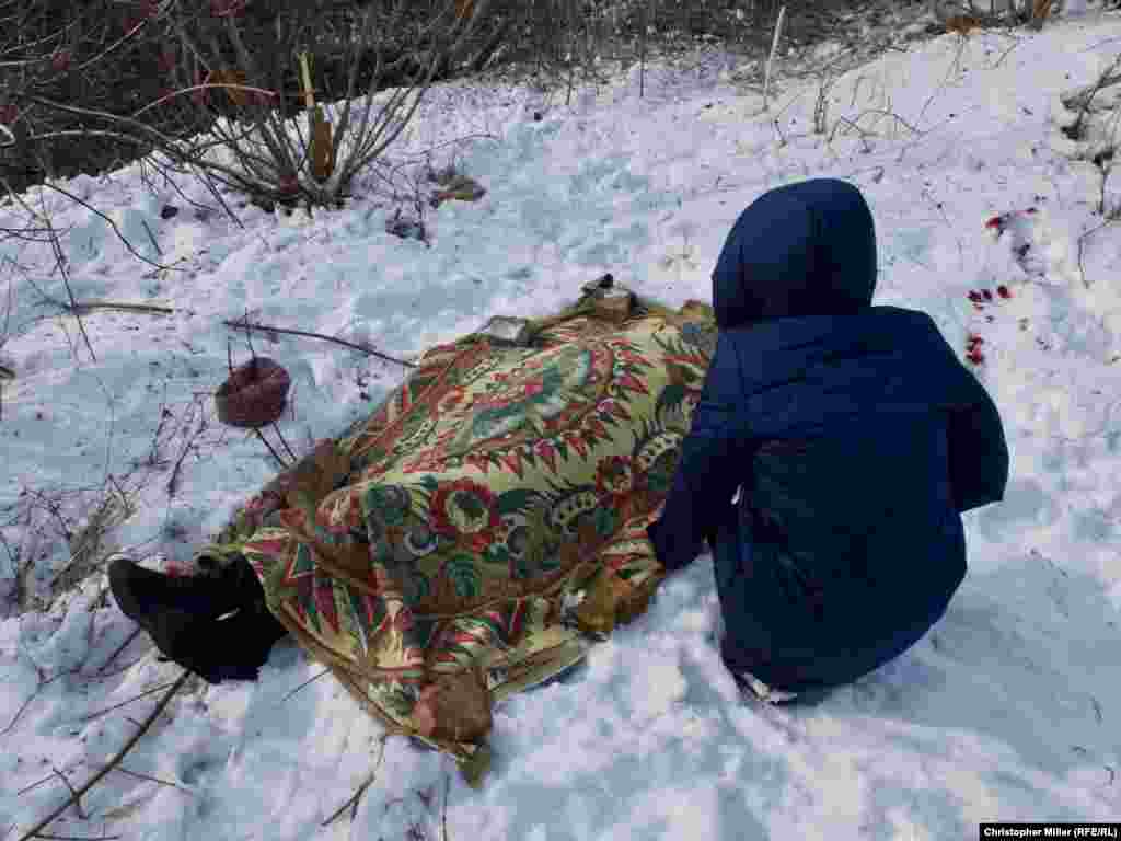 Nadia Volkova leans over the body of her mother, Katya, who was killed during shelling in the eastern Ukrainian city of Avdiyivka on February 1. (RFE/RL/Christopher Miller)