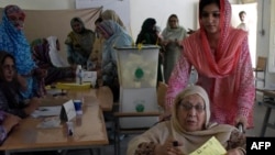 An elderly Kashmiri woman holds a ballot paper before casting her vote at a polling station in the general elections in Muzaffarabad, the capital of Pakistan-administered Kashmir on July 21.