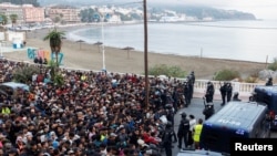 Policija prati migrante sa plaža španske enklave Seuta u privremeni kamp pored gradske luke, 18. septembar 2026. 