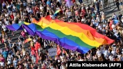 Njerëzit marshojnë me një flamur të madh me ngjyra ylberi gjatë një parade të homoseksualëve në Budapest, në vitin 2019.