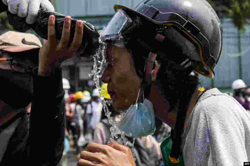A protester puts water on their face after tear gas was fired by police during a demonstration against the military coup in Yangon on March 2, 2021.
