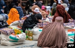Afghan women sit next to bags of food aid donated by the Indian government, in Kabul. (file photo)