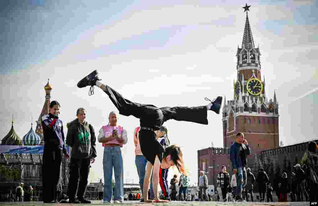 A Russian gymnast poses for a photo on Red Square in front of the Kremlin&#39;s Spasskaya tower and St. Basil&#39;s Cathedral in downtown Moscow.