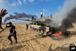 Палестинцы радуются уничтожению израильского танка у стены Израиля с сектором Газа, 7 октября 2023 года