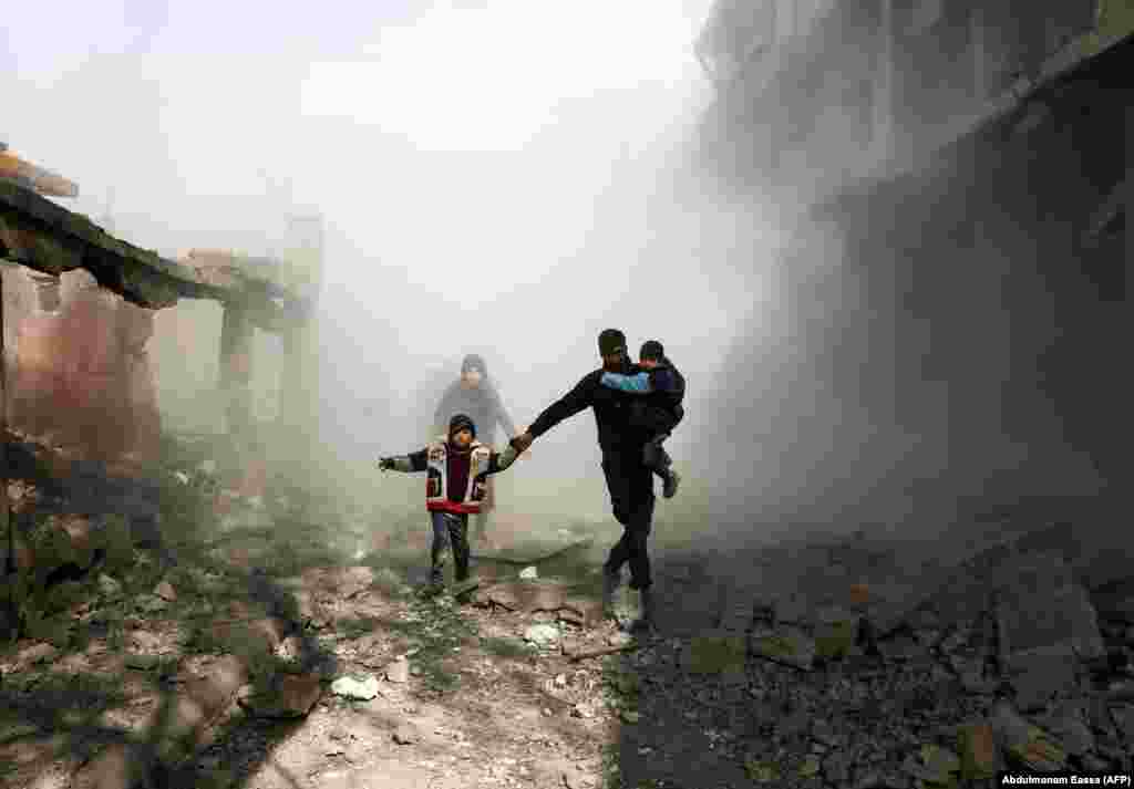 Syrian civilians flee from reported regime air strikes in the rebel-held town of Jisreen in the besieged Eastern Ghouta region on the outskirts of the capital, Damascus, on February 8. At least 22 civilians were reportedly killed. (AFP/Abdulmonam Eassa)