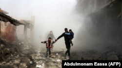 Syrian civilians flee from reported regime air strikes in the rebel-held town of Jisreen, in the besieged Eastern Ghouta region on the outskirts of the capital, Damascus, on February 8.