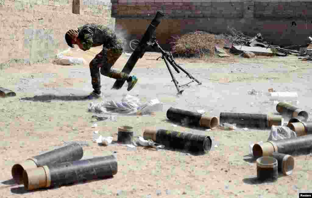 Syria -- A Kurdish fighter from the People's Protection Units (YPG) fires a 120 mm mortar round in Raqqa, June 15, 2017