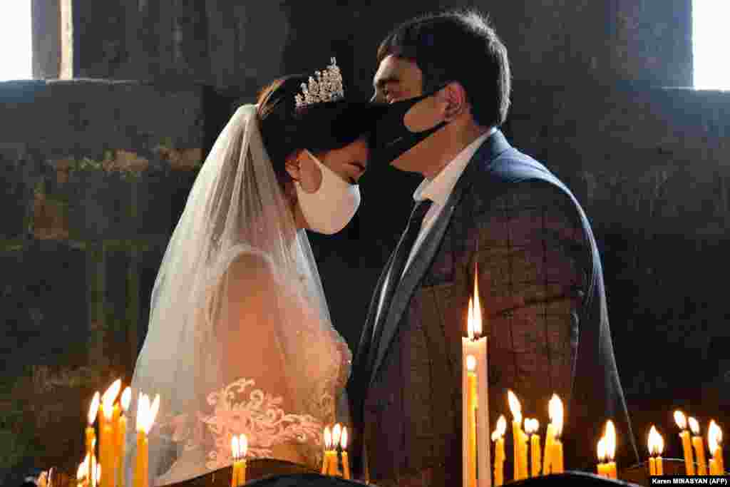 A bride and a bridegroom wearing protective face masks exchange kisses during a wedding ceremony at a church in a village outside Yerevan, Armenia. (AFP/Karen Minasyan)&nbsp; &nbsp;