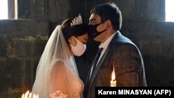 ARMENIA -- A bride and a bridegroom wearing protective face masks exchange kisses during a wedding ceremony in a church in Saghmosavan village on June 14, 2020.