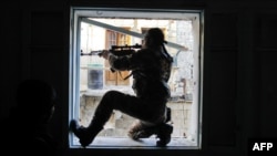 A member of Liwa Salahadin, a Kurdish military unit fighting alongside rebel fighters, aims at a regime fighter in the besieged district of Karmel al-Jabl in eastern Aleppo on December 6.