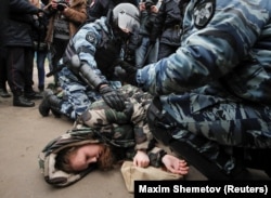 Police check a woman knocked down during a scuffle at the rally in Moscow.