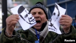 A protester tears a portrait of President Viktor Yanukovych.