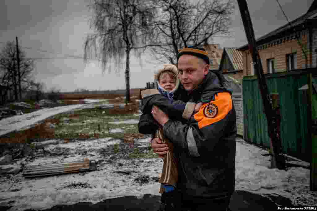 A rescue worker carries a child to the departure point.