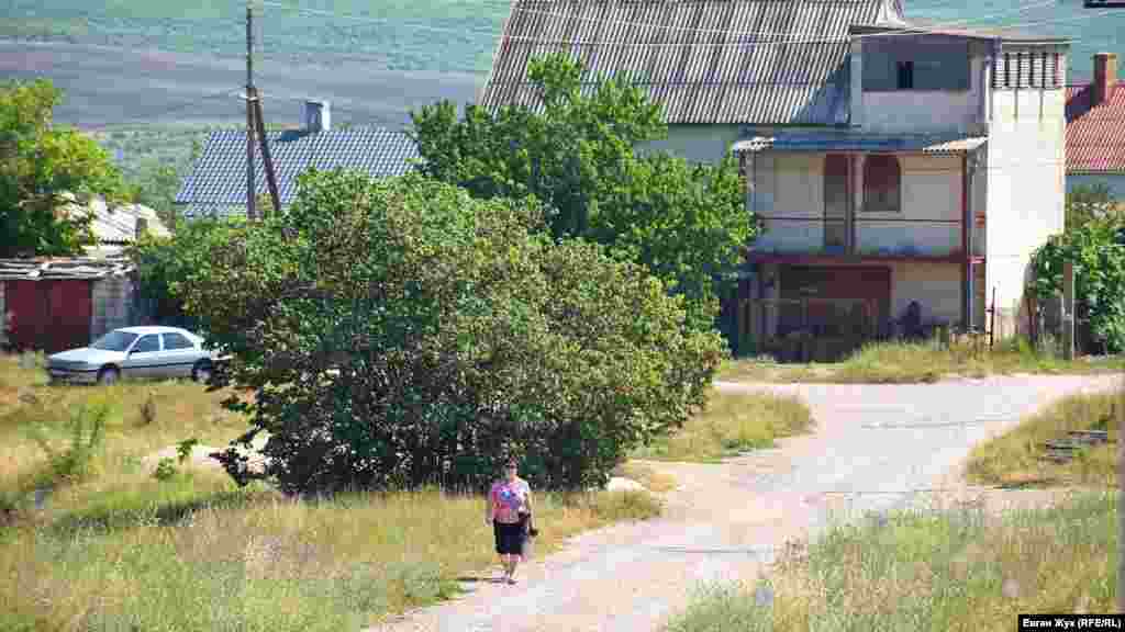 Местная жительница идет из села к остановке
