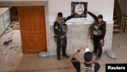 Iraqi special forces pose for a photograph in front of an Islamic States drawing inside a building east of Mosul on October 21.