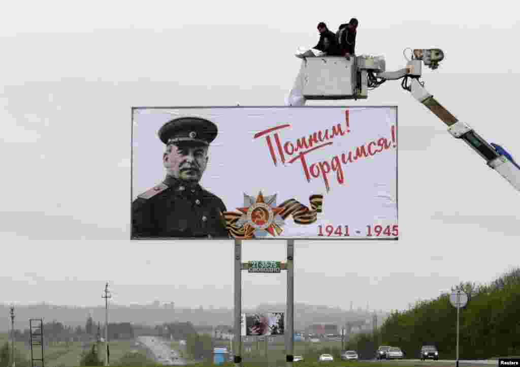 Işçiler Ýeňiş gününiň öňünden ozalky sowet diktatory Iosif Stalini wagyz edýän plakaty bejerýärler. Stawropol, Russia. (Reuters/Eduard Korniyenko)