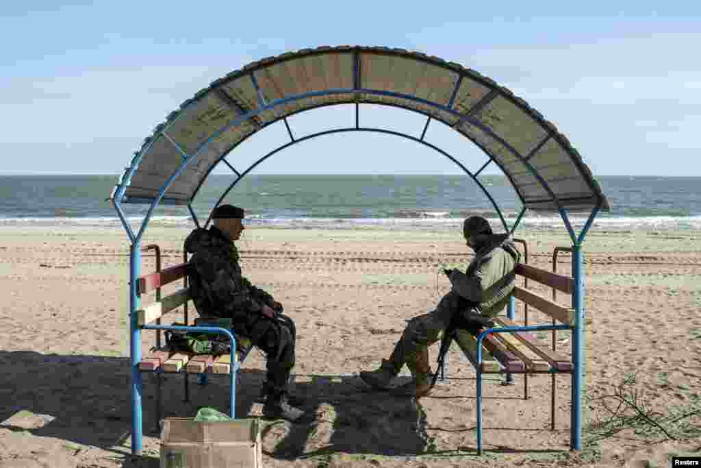 Ukrainian servicemen take a break from digging trenches on a beach in the port city of Mariupol on the Azov Sea on March 20. (Reuters/Marko Djurica)