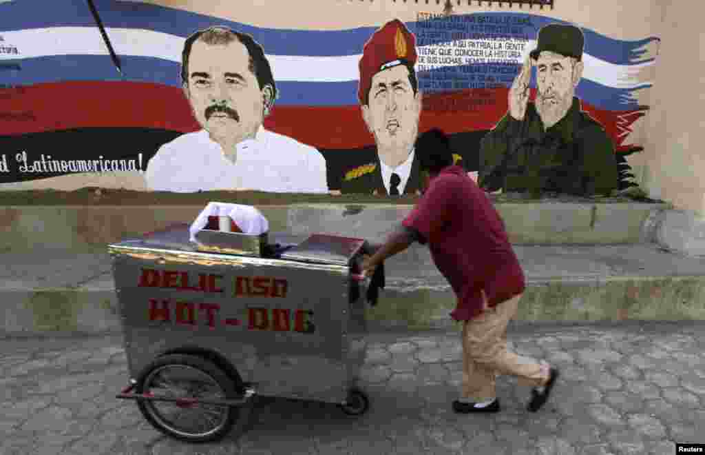 A street vendor in Managua, Nicaragua, pushes his cart past a mural depicting Venezuela's late President Hugo Chavez (center), former Cuban leader Fidel Castro (right), and Nicaraguan President Daniel Ortega. (Reuters/Inti Ocon)