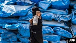 Një grua duke e mbajtur fëmijën e saj në një kamp të Sirisë. Fotografi ilustruese nga arkivi.