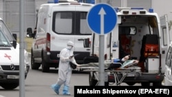 A Russian health worker escorts a COVID-19 patient to a hospital complex in Moscow, which has experienced a spike in coronavirus cases in the past week. 