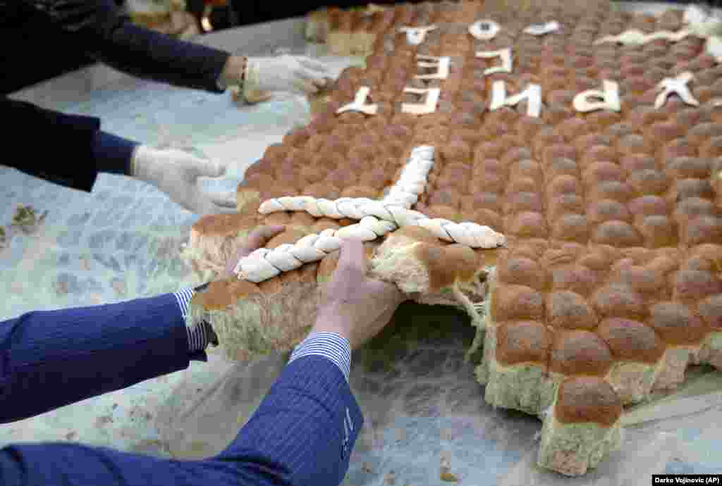 People break traditional Christmas bread to mark the Orthodox Christmas Day festivities in Belgrade, Serbia, on January 7. Children traditionally scramble for a piece of the bread, searching for a gold coin hidden inside. (AP/Darko Vojinovic)