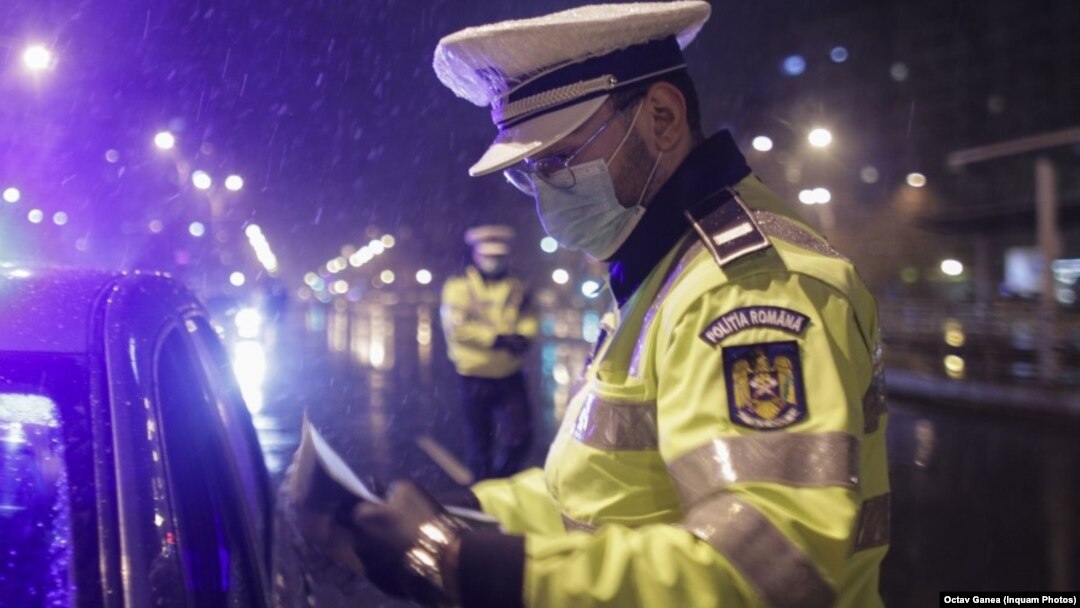 Un polițist, verificând documente, după instalarea restrcițiilor de circulație