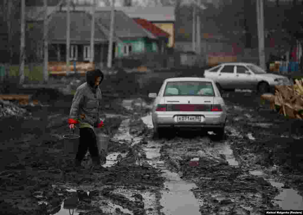 Жанчына нясе вёдры праз вуліцу ў горадзе Тара ў Омскай вобласьці Расеі. (Reuters/Alexey Malgavko)