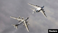 A Russian Tupolev Tu-95 strategic bomber refuels over an unknown location during a military exercise.