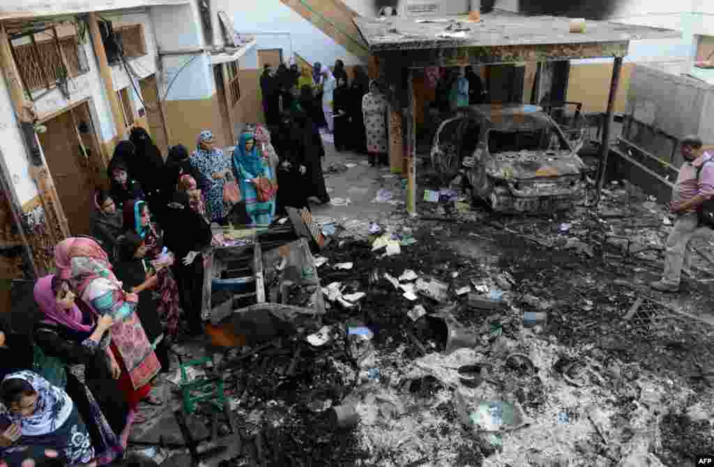 Teachers inspect the wreckage of a burned-out school in Lahore on November 3 after it was set on fire by an angry mob alleging that the school gave a test that insulted the Prophet Mohammed.