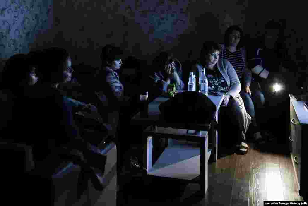 People watch state TV as they gather in a bomb shelter to protect against shelling in Stepanakert, the capital of the disputed region of Nagorno-Karabakh. Nagorno-Karabakh authorities reported that shelling hit Stepanakert and the towns of Martakert and Martuni. Clashes between Armenian and Azerbaijani forces over Nagorno-Karabakh entered a third day on September 29 as the two sides blamed each other for the hostilities amid international calls for an immediate end to the fighting. (Armenian Foreign Ministry via AP)