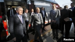 Russian President Vladimir Putin (center) and International Olympic Committee (IOC) President Thomas Bach (left front) exit a commuter train at a newly built railway station in Sochi on October 28.